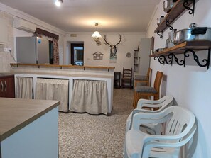A kitchen with a central island, wooden chairs, a chandelier, and a deer head decoration. - Casa Rural Villagarcia – Comfort and Privacy in El Real de la Jara (El Real de la Jara)