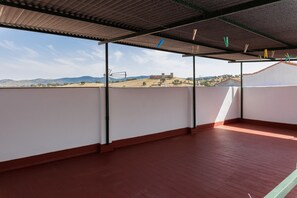 En takterrass med utsikt över avlägsna kullar och en byggnad.