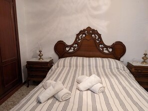Un lit bien fait, avec une literie à rayures, deux tables de chevet avec des lampes et une tête de lit en bois.