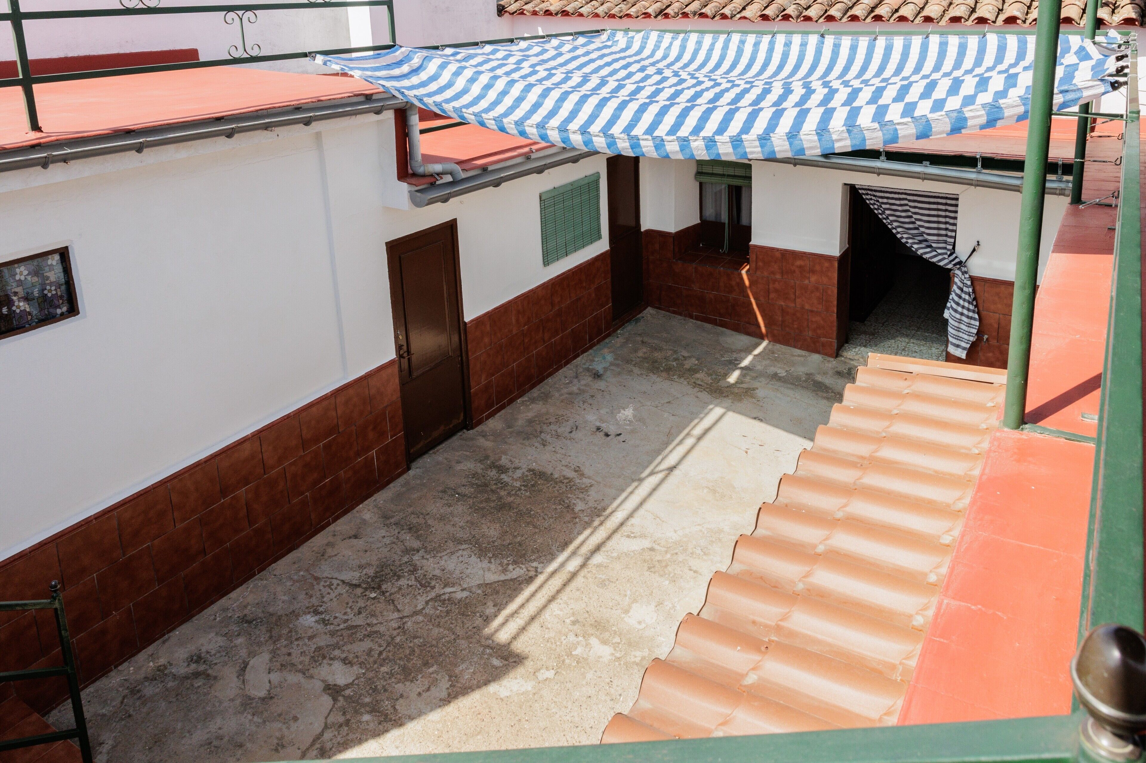 A covered outdoor area with a tiled floor, a door, and a window.
