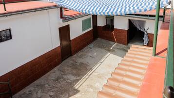 A covered outdoor area with a tiled floor, a door, and a window.