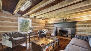 Ein rustikales Blockhaus-Interieur mit Kamin, Holzwänden und einer gemütlichen Sitzecke.