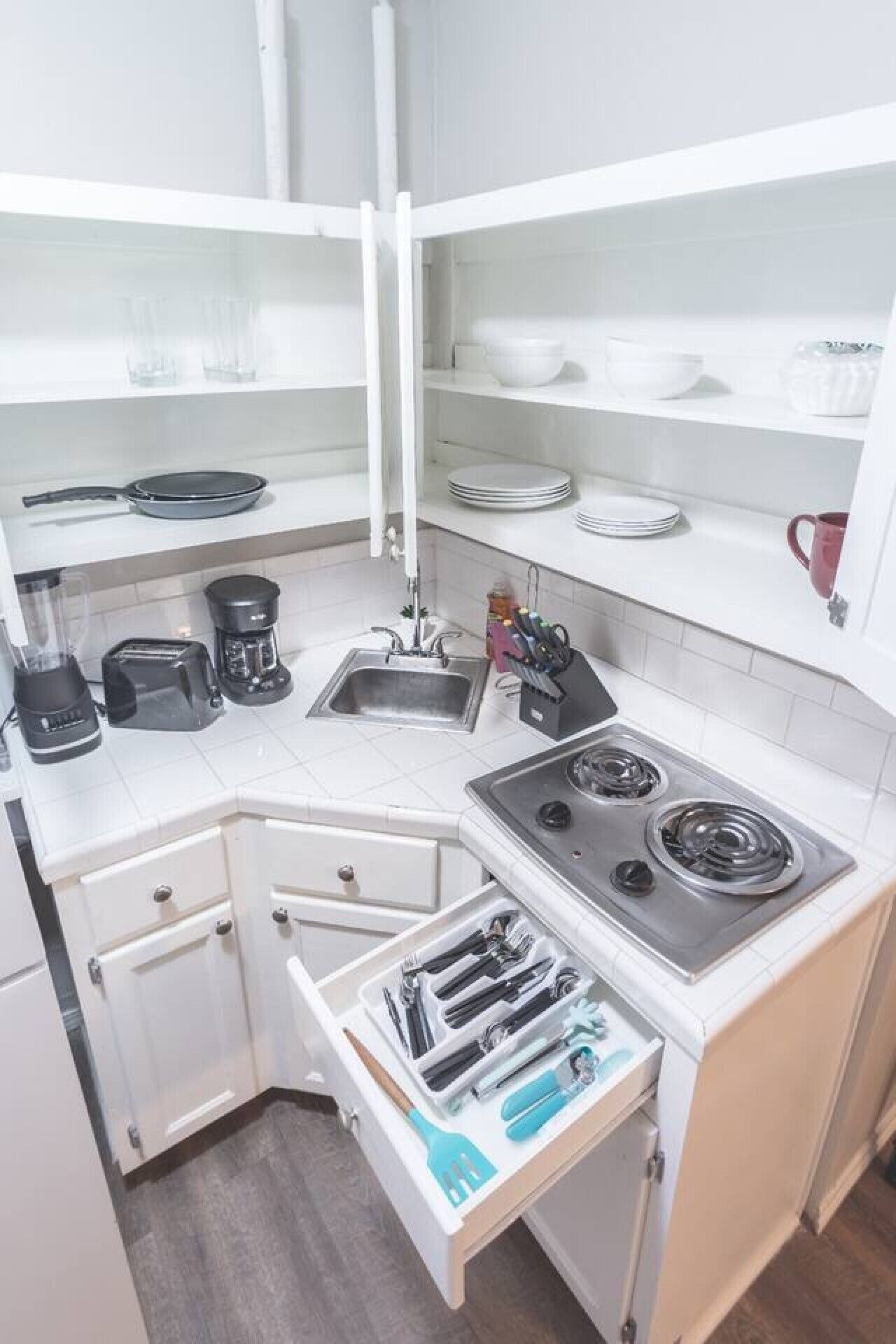 Een kleine keuken met een kookplaat, spoelbak en opbergladen.