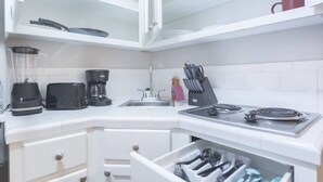Ett kök med en mixer, brödrost, kaffebryggare, diskho, spis och en låda för köksredskap.