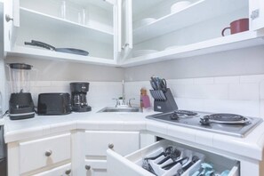 Una cucina con frullatore, tostapane, macchina del caffè, lavello, fornello e cassetto per utensili.