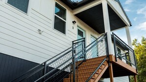 Een gebouw met twee verdiepingen, een trap, een balkon en een deur met een nummer.