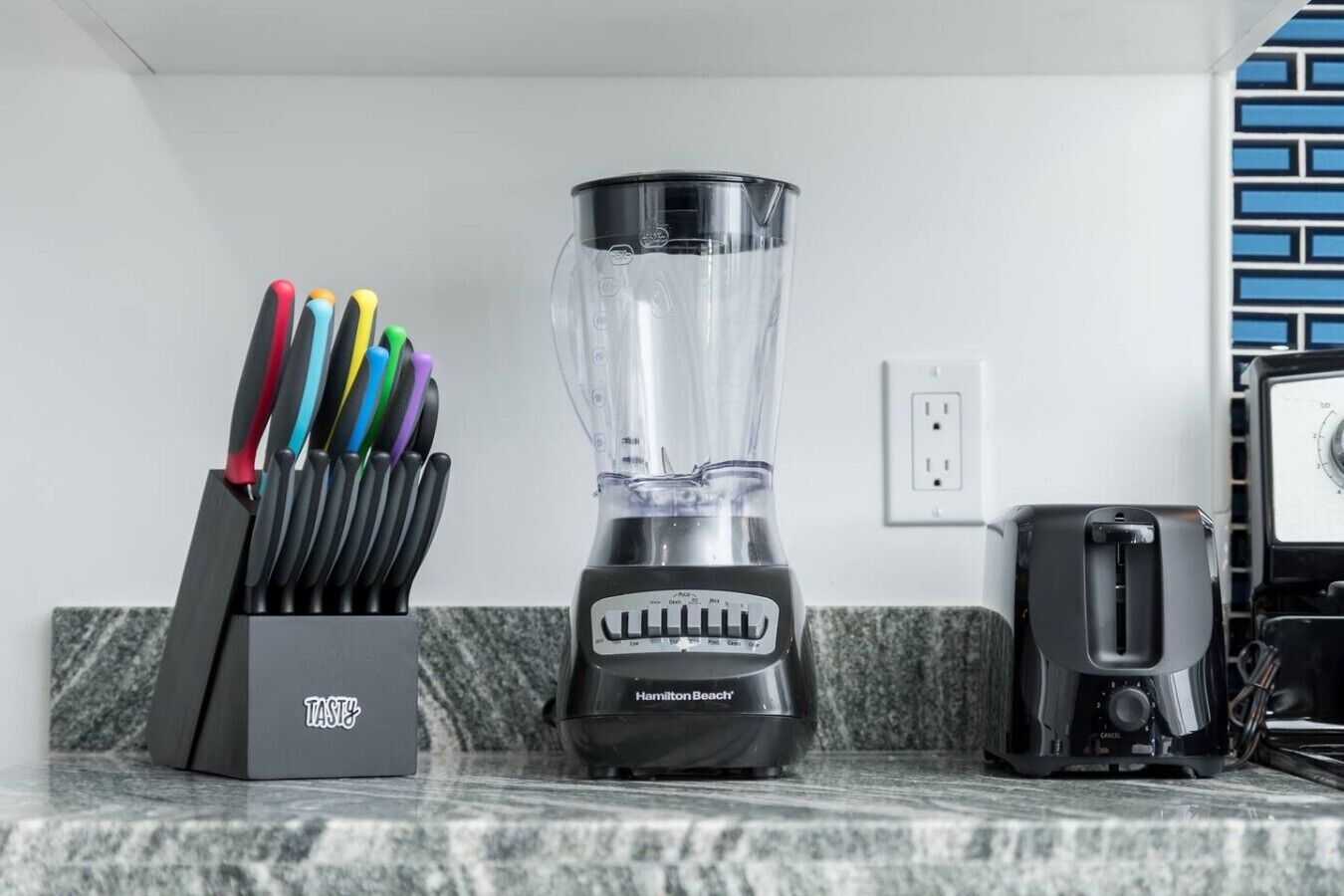A kitchen with a blender, a knife block, and a toaster.