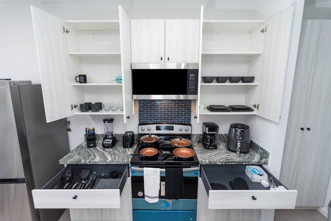 A compact kitchen with a stove, microwave, and coffee maker.