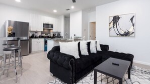 Een moderne woonkamer met een zwarte bank, een salontafel en een bar met krukken.