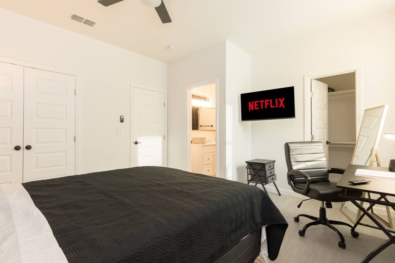 Ein Schlafzimmer mit einem Bett, einem Schreibtisch mit Stuhl, einem Fernseher und einer Tür zu einem Badezimmer.