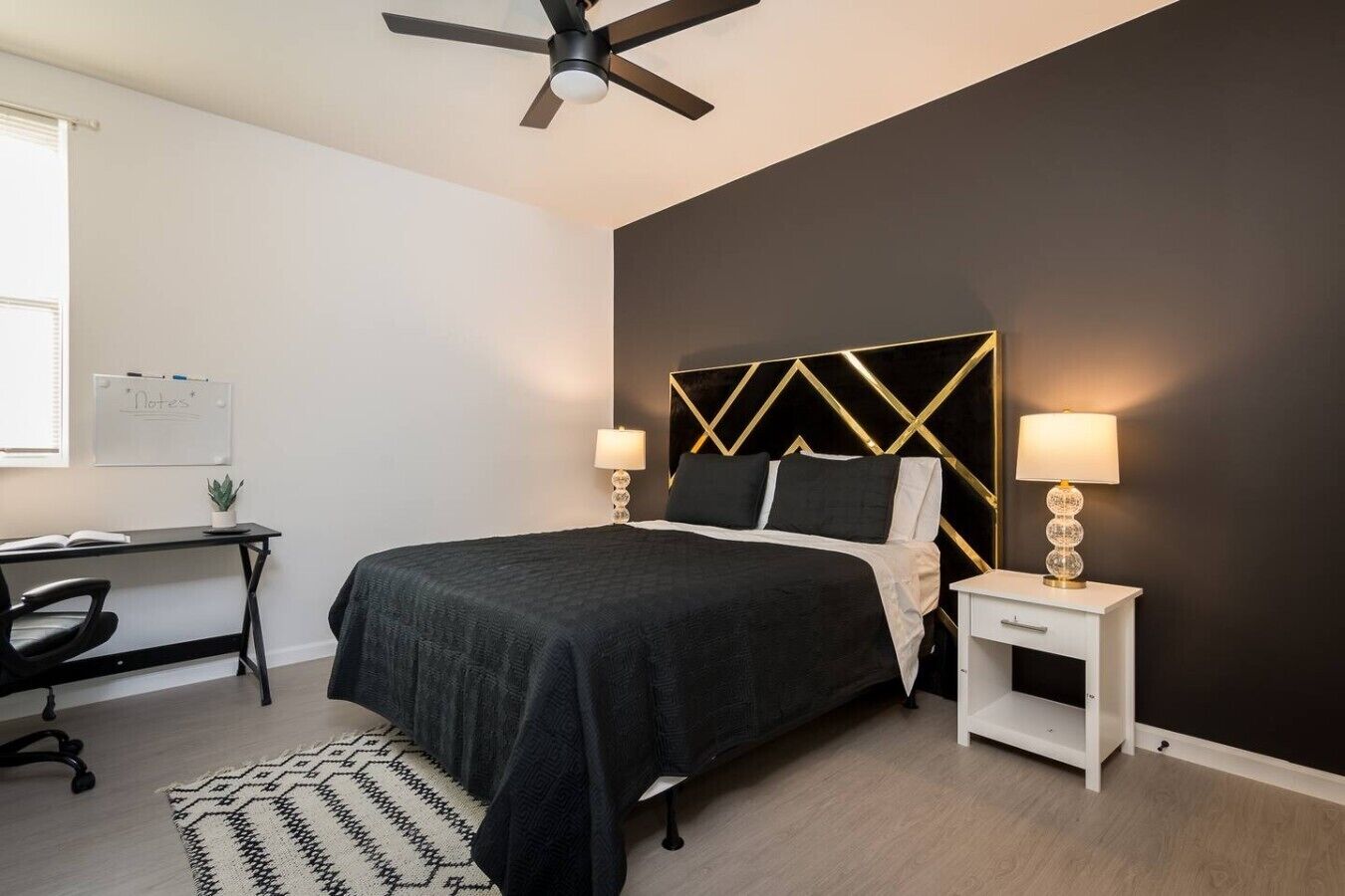 Ein Schlafzimmer mit Bett, Schreibtisch, Stuhl und Deckenventilator.