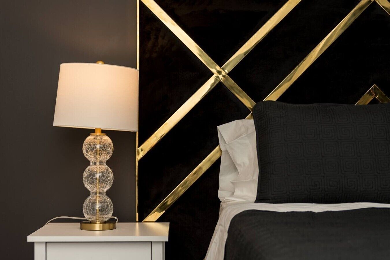 A bed with a black headboard, a white pillow, and a black blanket.