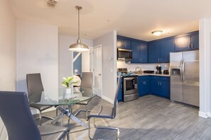 Eine moderne Küche mit blauen Schränken, Edelstahlgeräten und einem Glastisch mit Stühlen.