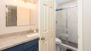 A bathroom with a vanity, sink, mirror, and a glass shower enclosure. - King Bed, Central Location  Fast WiFi / Long Term (McAllen)