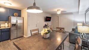 A modern kitchen with a stainless steel refrigerator, a dining table with chairs, a TV mounted on the wall, and a ceiling fan. - King SIze 🛏 Fast WiFi 📶Central Workspace & Cozy✅ (McAllen)