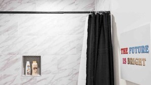 Un bagno con parete in marmo, tenda da doccia e una citazione motivazionale sulla parete.
