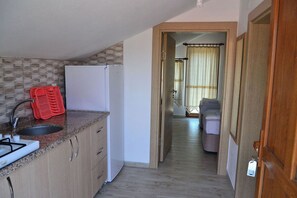 A compact kitchen with a sink, a red dish rack, and a white refrigerator.