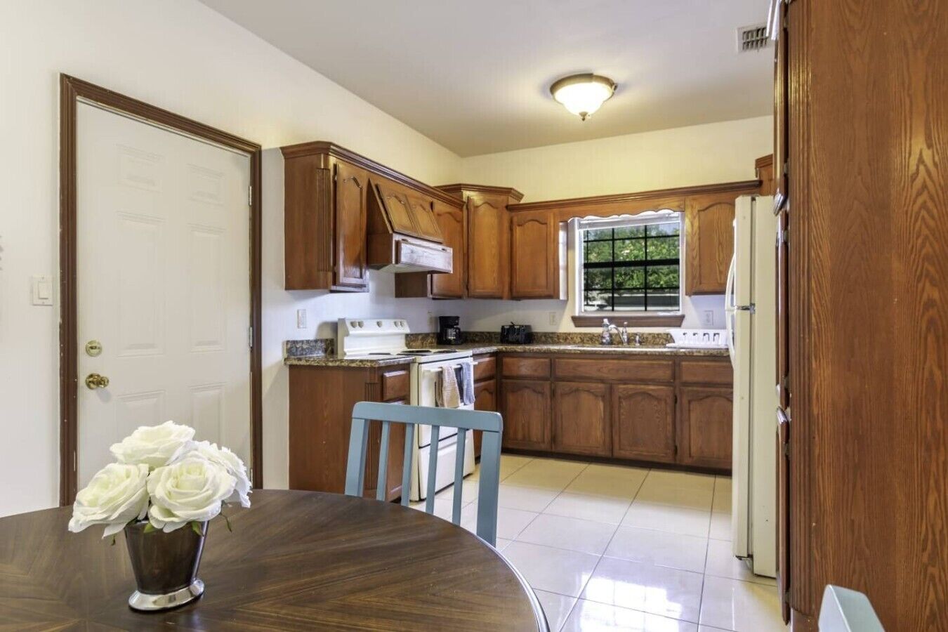 A kitchen with wooden cabinets, a stove, a sink, and a window.