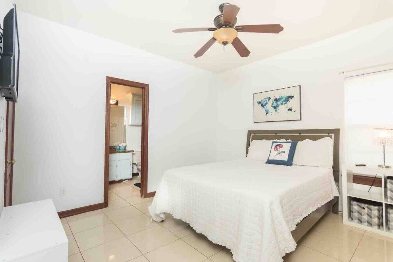 Ein Schlafzimmer mit einem Bett, einem Deckenventilator, einem gerahmten Bild und einem Nachttisch.