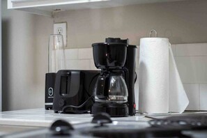 Une cuisine équipée d’une machine à café, d’une verseuse en verre et d’un rouleau d’essuie-tout.