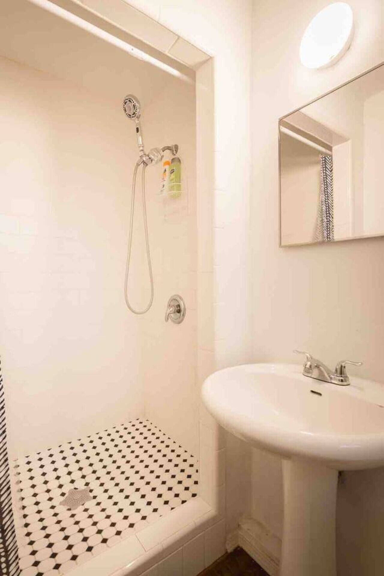 A bathroom with a shower, a sink, and a mirror.