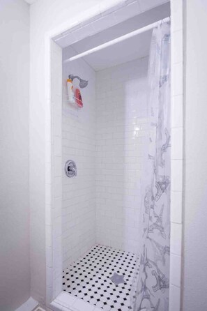 Eine Dusche mit gefliestem Boden und einer Duschvorhang.