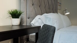 Et pænt hotelværelse med seng, natbord med en potteplante, stol og lampe.