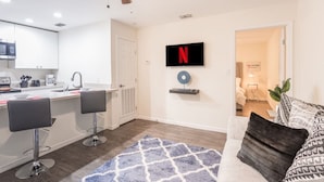En moderne lejlighed med et køkken, en opholdsstue med sofa og TV, samt en loftventilator.