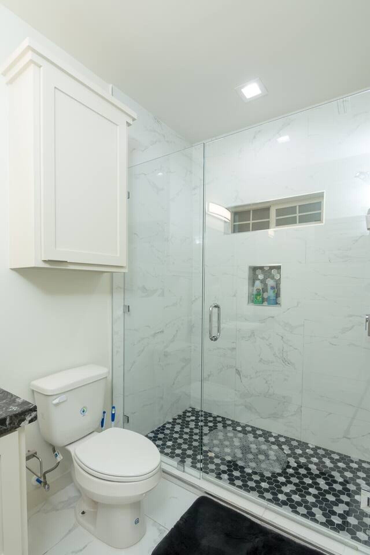 Een badkamer met toilet, douchecabine en betegelde vloer.