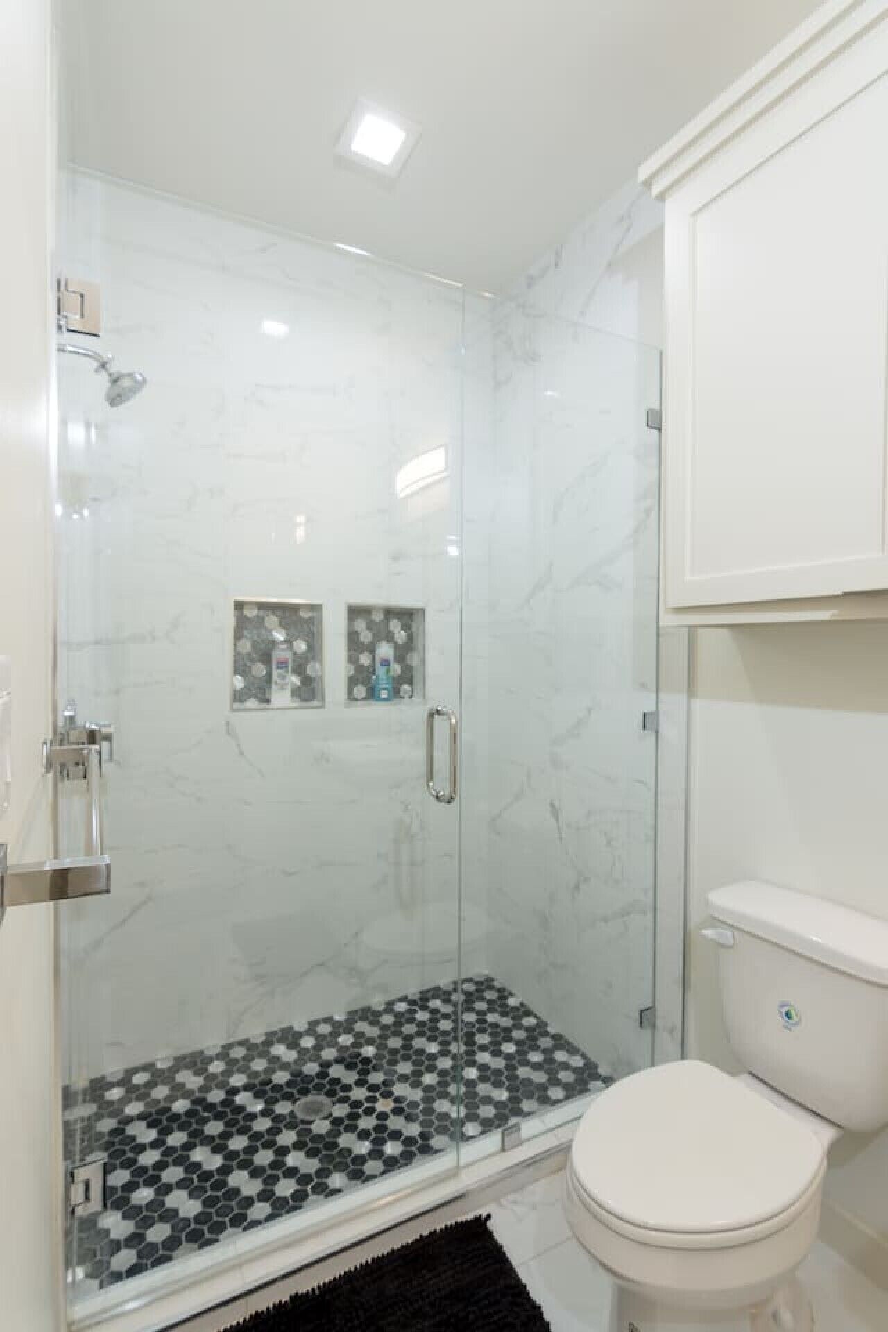 Une salle de bain avec une douche à parois de verre, des toilettes et un lavabo.