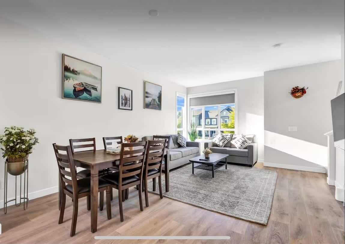 A modern living room with a dining area, a sofa set, a coffee table, and a large window with a view of buildings.