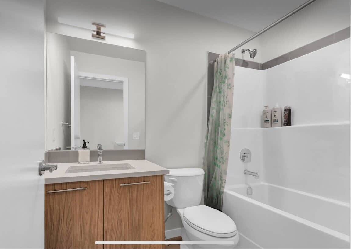 A modern bathroom with a toilet, sink, vanity, and shower.