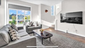 Ein modernes Wohnzimmer mit einer Sofagarnitur, einem Couchtisch und einem an der Wand montierten Fernseher.