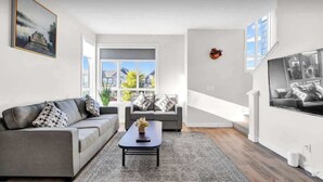 Ein modernes Wohnzimmer mit einem grauen Sofa, einem Couchtisch und einem großen Fenster.