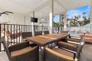 An outdoor patio with wicker furniture, a pool, and a TV screen. - Pool, Putting Green, Boat Parking, Giant Sand Pit, Steps to Beach (Port St. Joe)