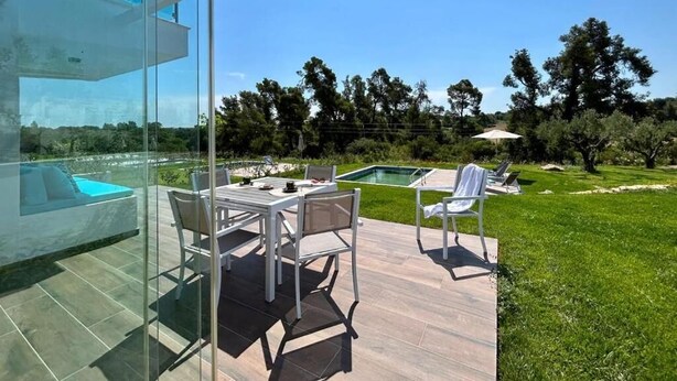 Eine moderne Außenpatio mit Glasveranda, Pool und Rasenfläche mit Bäumen.
