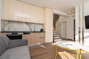 Eine moderne Küche mit Marmor-Spritzschutz, eingebauten Geräten und einer Treppe, die zu einer zweiten Etage führt.