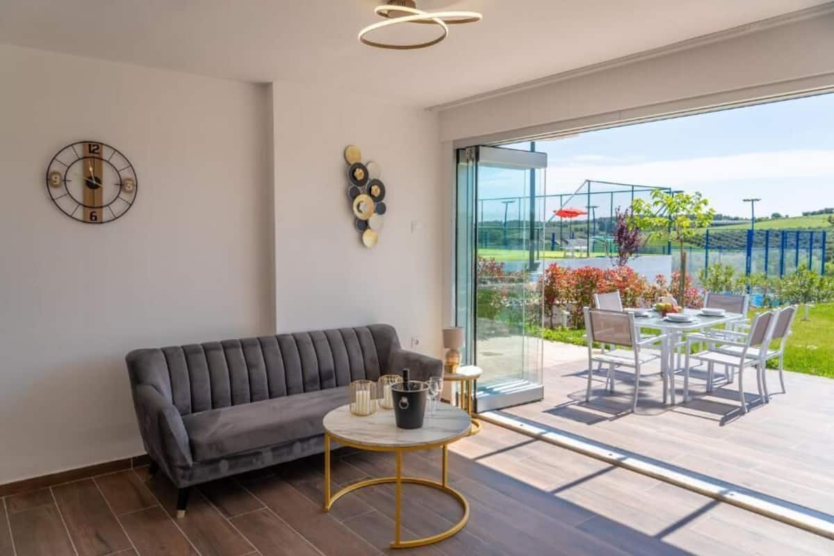 Un salon moderne comprenant un canapé, une table ronde avec un pied doré et un coin repas avec des chaises et une table.