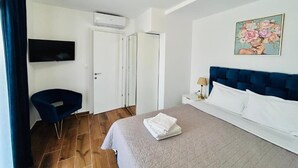 Ein Hotelzimmer mit einem Bett, einem Fernseher, einem Schreibtisch und einem Bild an der Wand.