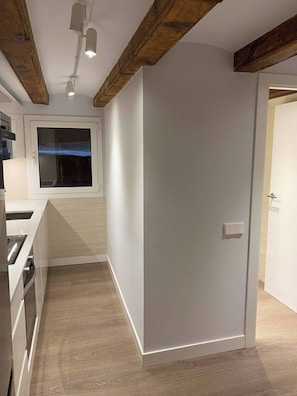 Eine moderne Küche mit Einbauofen, Fenster und Holzbalken an der Decke.