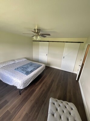 Ein Schlafzimmer mit Bett, Deckenventilator, Kleiderschrank und einer kleinen Sitzecke.
