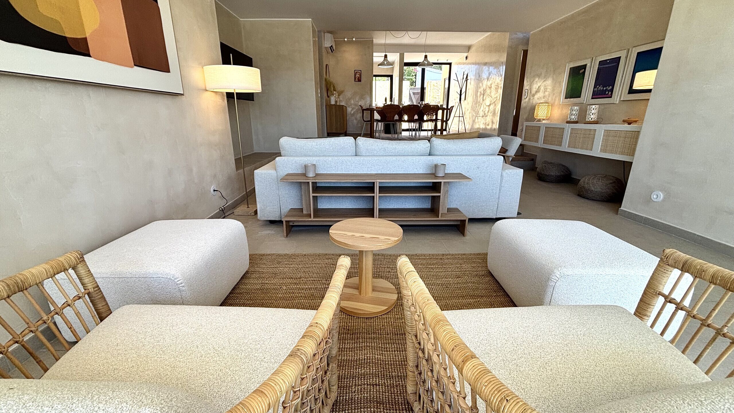 Ein modernes Wohnzimmer mit einer Couch, zwei Sesseln, einem Couchtisch und einem Essbereich mit Stühlen und Tisch.
