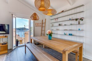 Una sala de estar moderna con un banco de madera, un televisor, una estantería y vistas al exterior.