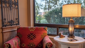 A room with a patterned armchair, a table with a lamp, and a decorative wall piece. - Luxury Sedona Views, Spa, Sauna, Cold Plunge (Sedona)