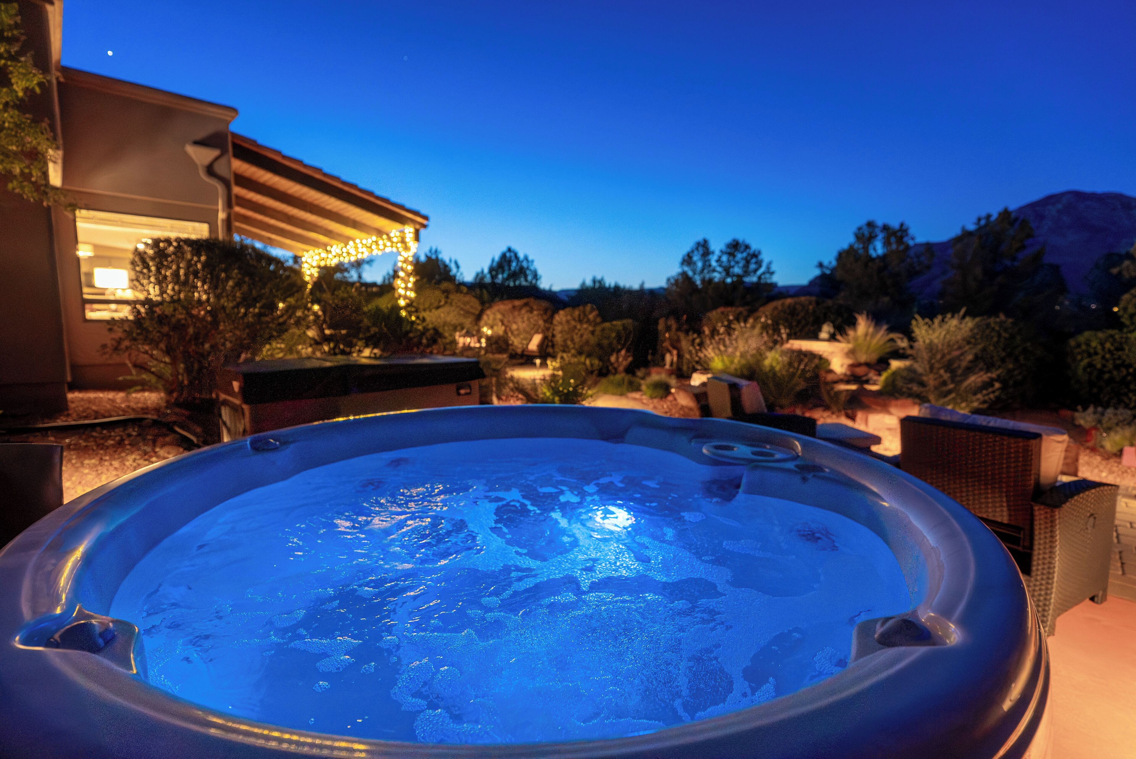A hot tub in a backyard with a house in the background.