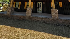 Ein modernes Haus mit überdachter Veranda, einem Natursteinfundament und einem Metalldach.