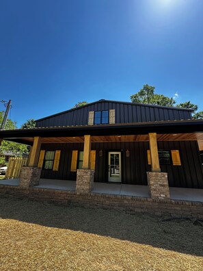 Ein modernes Haus mit überdachter Veranda, einem Natursteinfundament und einem Metalldach.