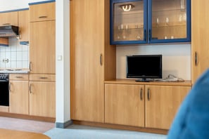 A kitchen with wooden cabinets, a built-in stove, and a television on a countertop.