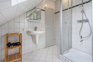 Une salle de bain moderne avec une douche, un lavabo et une étagère en bois.