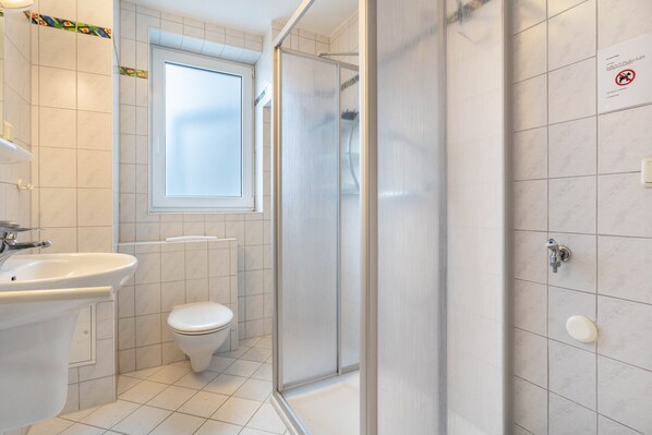 A bathroom with a sink, toilet, shower, and a window. - Apartment 'Ringstr. 20, 3. OG Rechts WE68' with Balcony and Wi-Fi (Binz)